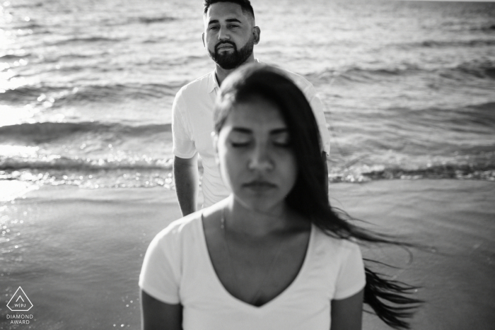 un couple, ensemble sur la plage lors d'une séance de fiançailles Western Australia Perth Couple, ensemble sur la plage. | Engagement Couple Session - L'image contient: eau, vagues, sable, noir, blanc, vent, cheveux