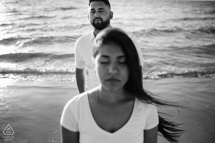 Western Australia Perth Couple, Together on the beach. | Engagement Couple Session - Image contains: water, waves, sand, black, white, wind, hair