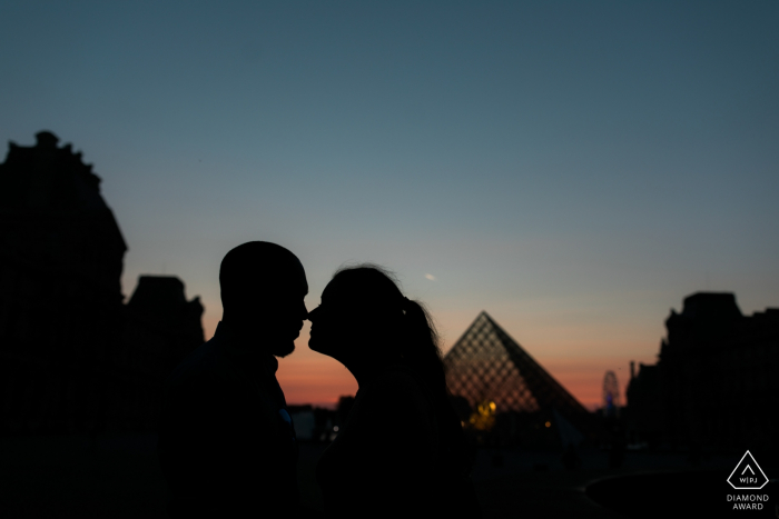 Silhouettieren Sie Schuss von rührenden Köpfen eines Paares während der blauen Stunde nahe dem Louvre in Paris - Verpflichtungsphotographie