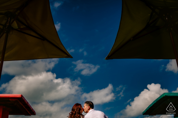 Photo by: <a href="https://www.wpja.com/photos/diamond-award-top-wedding-engagement-photographer/2571206">Michael Freas - Key West Florida Sunset Pier,Key West, Florida Engagement Photographer: Used the bar tops and umbrellas to create symmetry, while I used the blue sky for a clean background