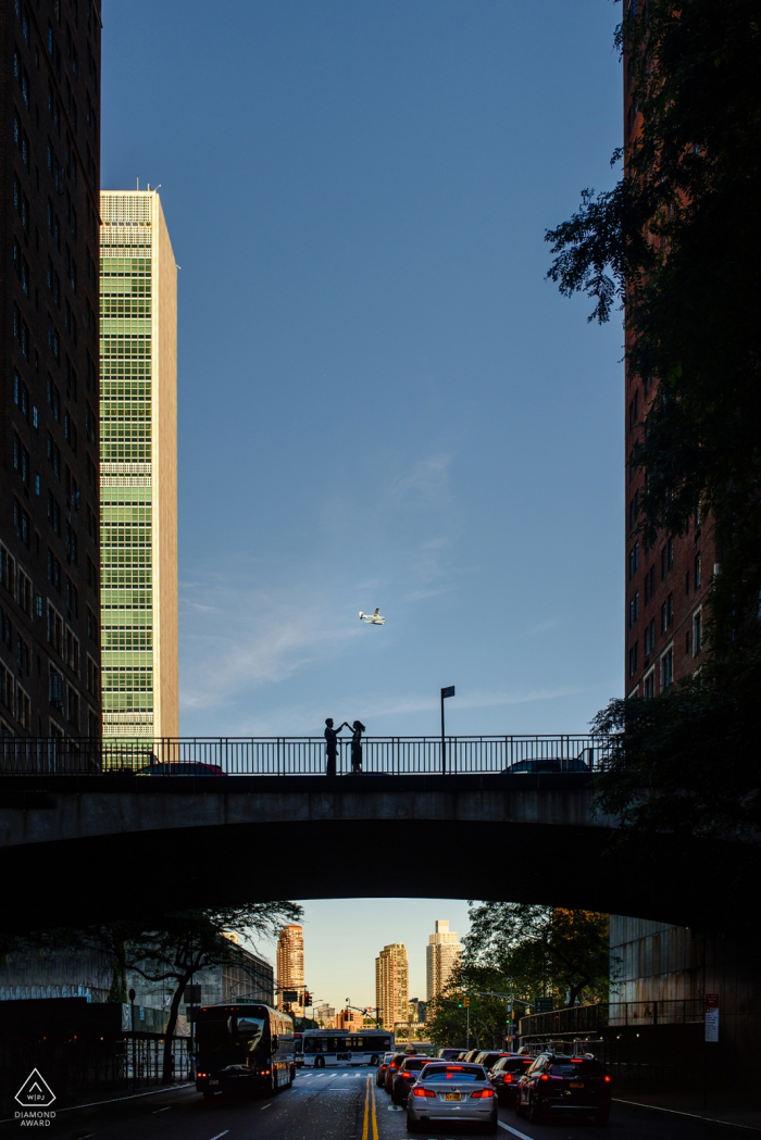 a Couple dances on the bridge during engagement portrait session Tudor City, Manhattan Couple dances on the bridge during engagement portrait session.