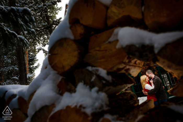 Breckenridge, CO portraits de mariage pré. - Encadrement du couple avec une pile de bois pour leur séance de fiançailles d'hiver à Breckenridge.