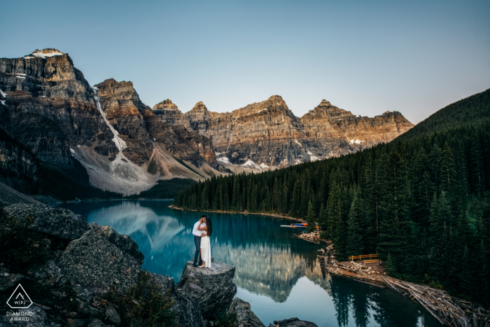 Moraine Lake, Banff National Park, AB, Canada | Golden hour before the sunrise | Engagement Couple Photography - Portrait contains: water, mountains, cliff, view, hug