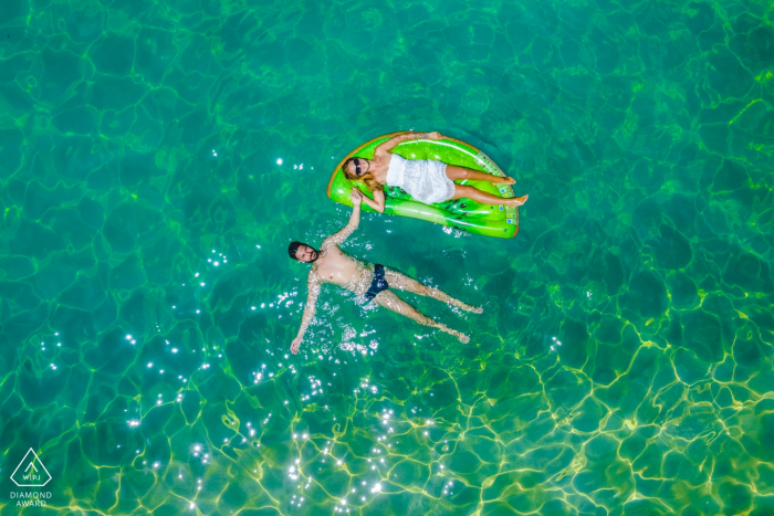 Photo by: <a href="https://www.wpja.com/photos/diamond-award-top-wedding-engagement-photographer/2572267">Simona Cancelli - Siracusa Siracusa Carlentini summer loving - engagement portrait shot with overhead drone of a couple relaxing in the water.