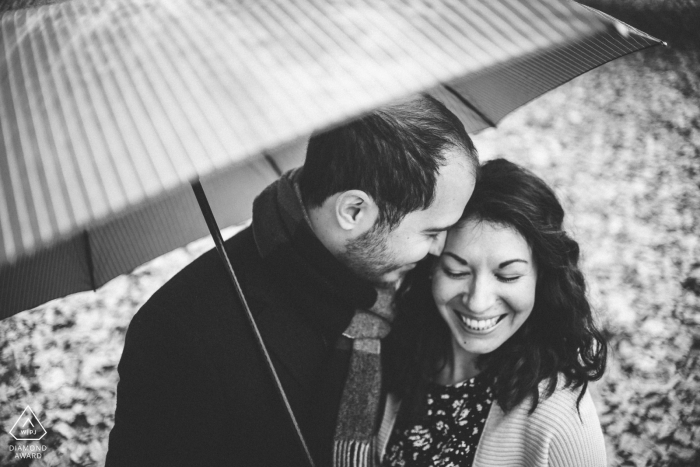 Fotografia de noivado da Attica de um casal rindo sob um guarda-chuva