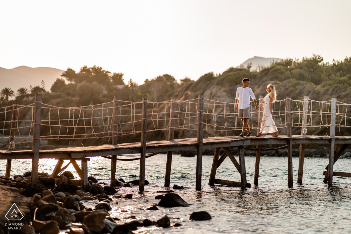 Zakynthos, Grèce Portraits de fiançailles au coucher du soleil en Grèce - Un couple sur la promenade au-dessus de l'eau.