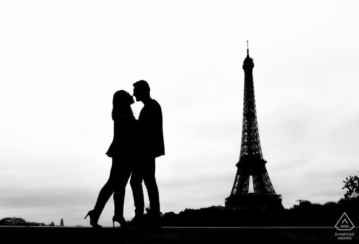 Foto de silhueta de um casal se beijando em frente à Torre Eiffel durante uma sessão de noivado