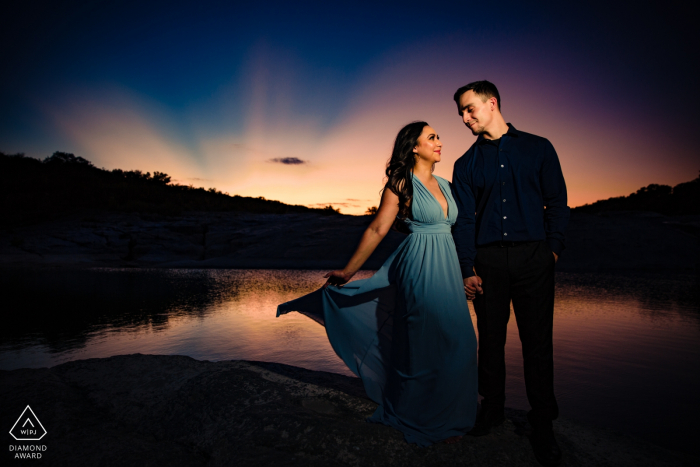 Séance de portrait de fiançailles au coucher du soleil au parc d'État de Pedernales Falls au bord de l'eau