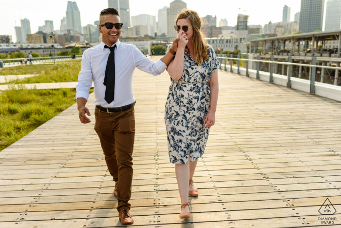 Engaged couple walking on boardwalk, woman kissing man's hand - Old Montreal, Canada portrait session