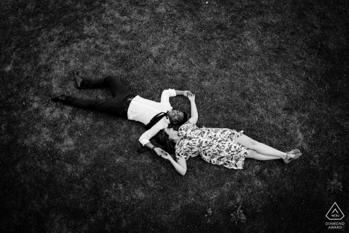 Montreal, Quebec Black and white engagement photo of couple lying in the grass seen from bird's eye view 