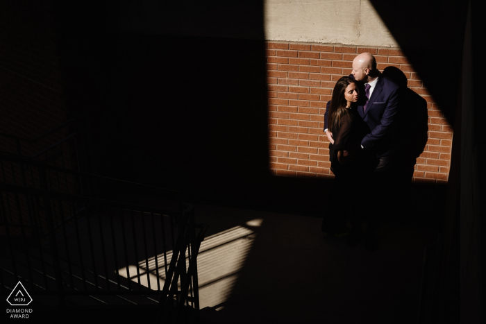 The Pearl Brewery Engagement Photo Session | Couple in the light with angled shadows in a parking lot 