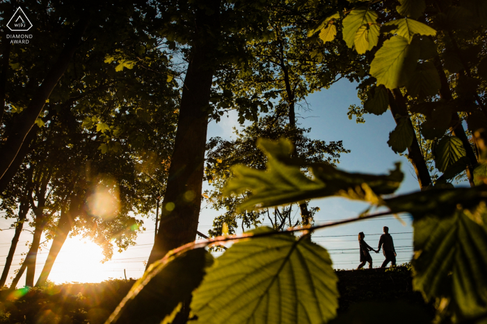 Sint-niklaas, prywatny fotograf terytorium: para spaceruje po szynach pociągu podczas zachodu słońca