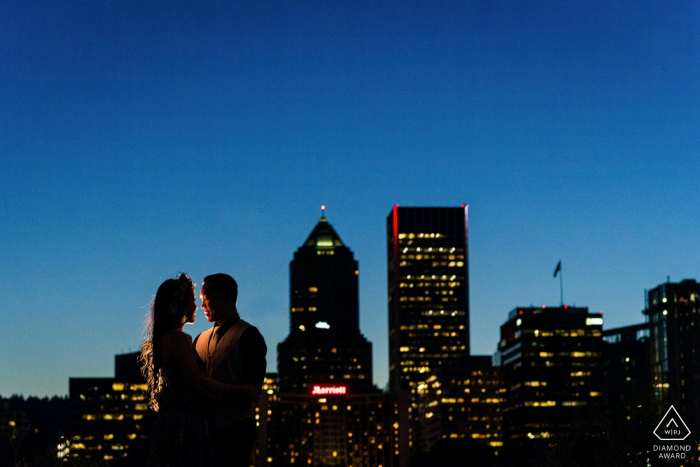 Couple share their loving engagement photo session with the background of the city skyline at dusk Couple share their loving engagement photo session with the background of Portland Oregon