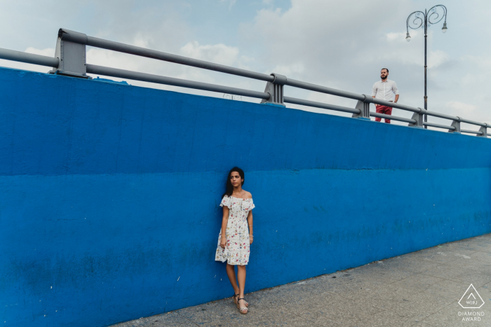 Photo by: <a href="https://www.wpja.com/photos/diamond-award-top-wedding-engagement-photographer/2579318">Federica Ariemma - Napoli Napoli Cuba engagment shoot against a highway wall that is painted blue.