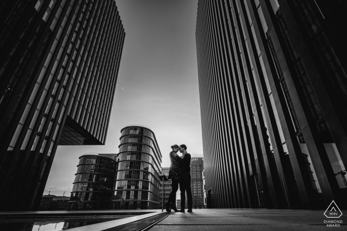 Photos de fiançailles de Düsseldorf dans la ville avec de grands immeubles et un jeune couple amoureux