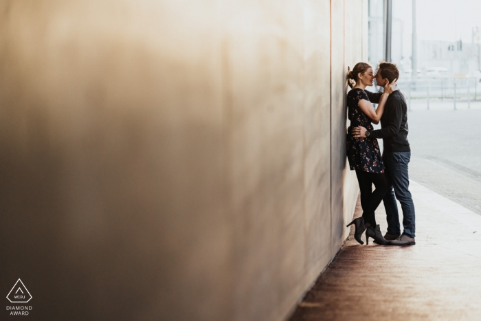 Coppia sparare nel mezzo di Düsseldorf contro un muro pulito e semplice, con un bacio