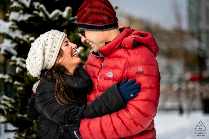 Incek, Ankara, Turquía Retratos previos a la boda: la pareja de pie frente a un árbol se abraza, se mira y se ríe bajo la nieve