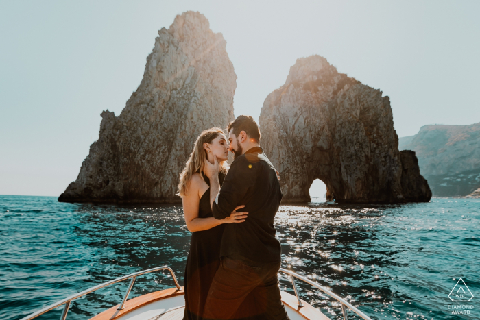 Foto previa a la boda de la isla de Capri en la parte delantera de un barco cerca de las rocas en el agua.