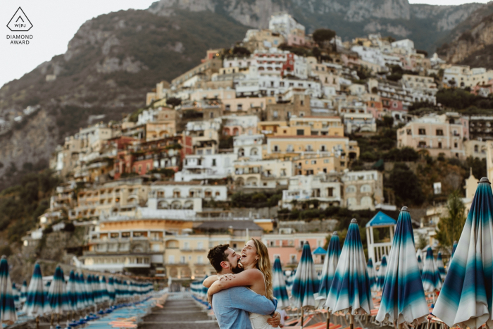 Coppia ridere di fronte alle montagne di Positano durante la sessione di foto di fidanzamento.