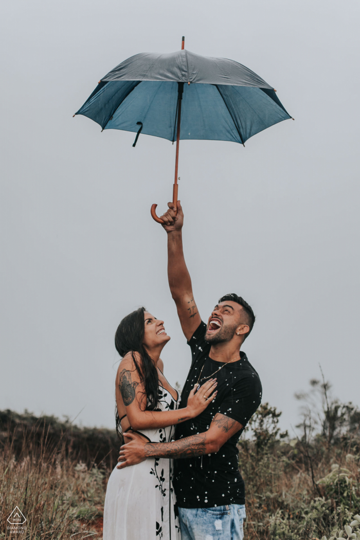 Ehepaar aus Belo Horizonte, Brasilien, hält einen Regenschirm in der Hand und genießt ihre Verlobungsfotosession.