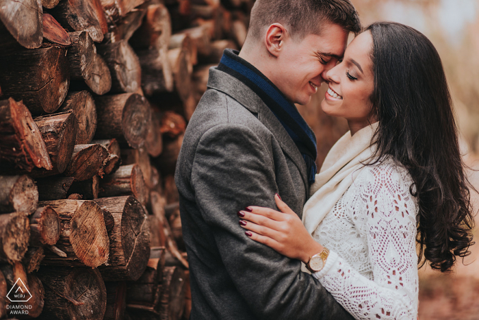 Rio Grade do Sul engagement shoot of a couple holding each other near a stacked wood pile.