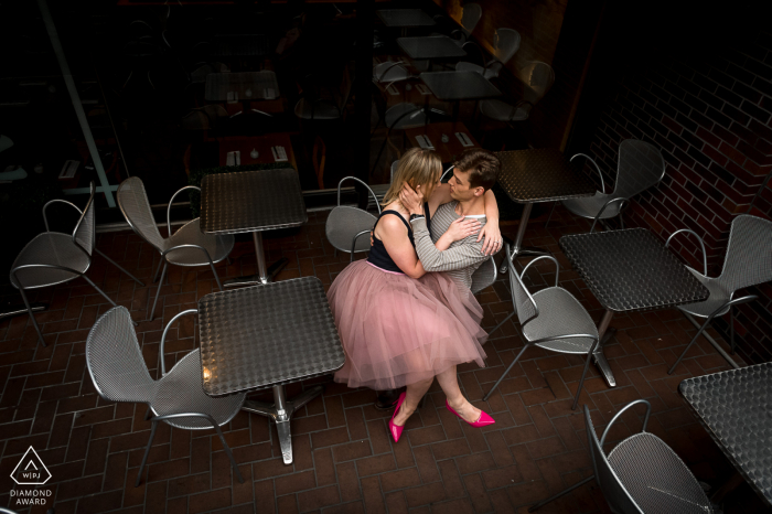 Engagement image of a couple sitting in silver chairs in cafe Yorkville, Ontario.