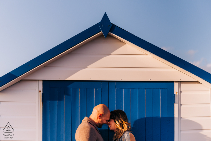 engagement Pictures showing Close up of couple embracing, framed by a beach hut Shoreham Beach, West Sussex, UK Pictures - Close up of couple embracing, framed by a beach hut