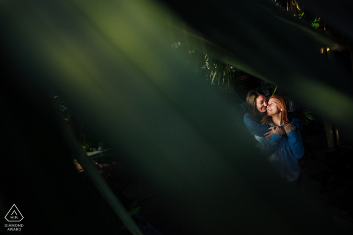 Engagement Sessions |  This photo is taken inside a greenhouse at Rawlings Conservatory in Baltimore. There was a beam of harsh sunlight coming through the window that I positioned the couple in and then shot through the leaves of one of the plants