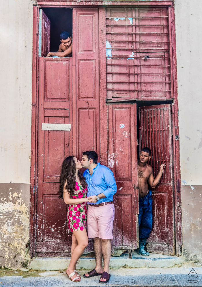 Couple Engagement Photo Session | A couple stop for a kiss while exploring a Havana neighborhood 