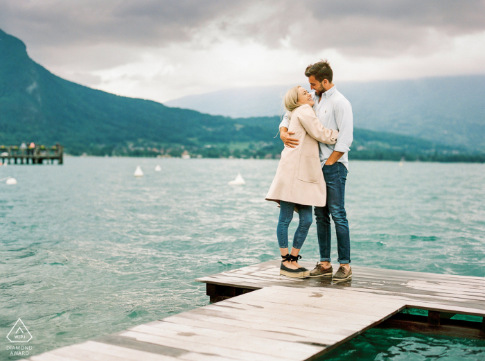 Couple Engagement Photo Session with A couple on a wooden dock in front the lake Couple Engagement Photo Session | A couple in front Annecy lake