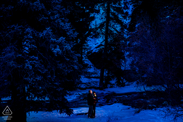 A couple during a blue hour portrait in the winter mountains A couple during a blue hour portrait in Bailey, Colorado