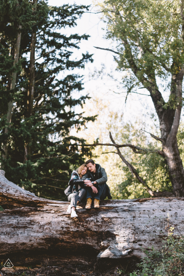 An enaged couple in a forest sitting on a giant log in Kifissia, Greece