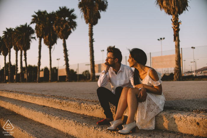 A couple sitting by the beach watching the sunset palm trees in Glyfada, Greece 