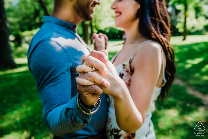 Casal cara a cara estende as mãos para um retrato de noivado em Toronto, Ontário