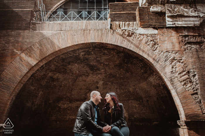 Ritratto di fidanzamento di una coppia incorniciata all'interno di un arco a Roma, Italia