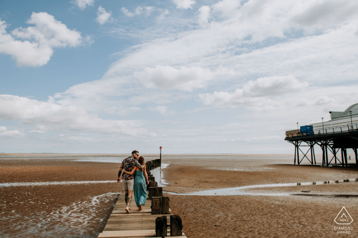 Lincolnshire, Reino Unido retrato de compromiso | Zara y Alex caminan por la playa en Cleethorpes al comienzo de su sesión previa a la boda.