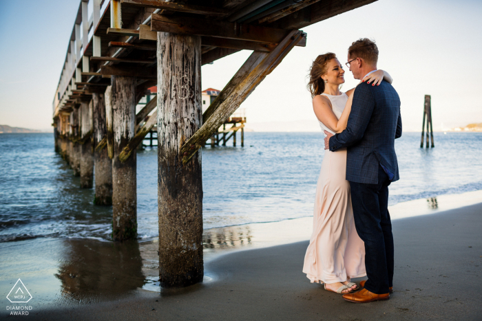 An embrace under the pier during an engagement shoot in San Francisco