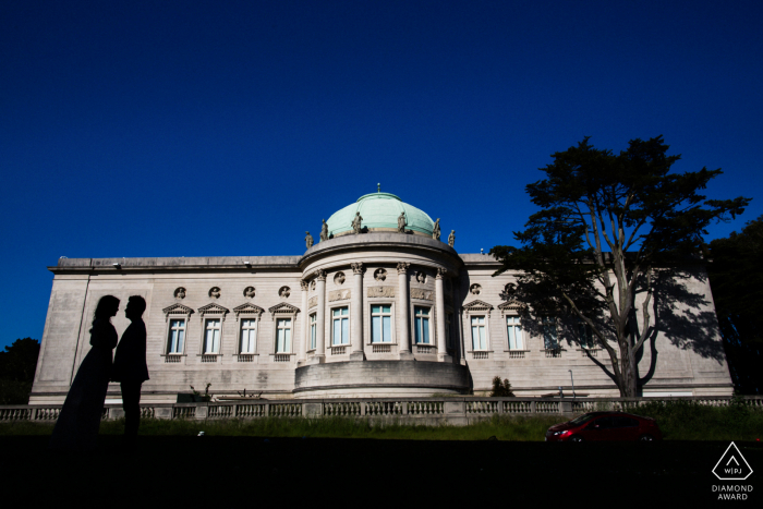 Casal de San Francisco silhueta contra um prédio durante sua sessão de retrato de noivado