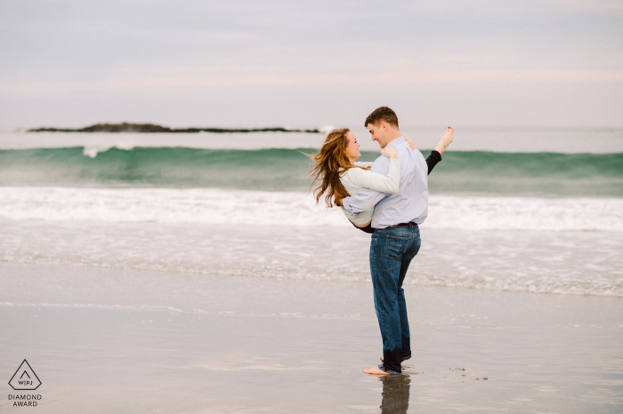 A couple enjoying the seaside beach during an engagement photography session A couple enjoying the seaside beach in York Harbor Beach, Maine during an engagement photography session
