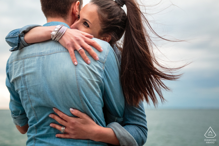 Sessão de retrato de noivado em Trieste, Itália, no mar, com amor, vento e abraços