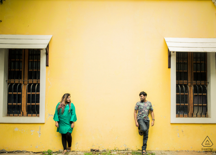 Pudhucherry, India couple Exchanging love against a blank yellow wall during portrait session