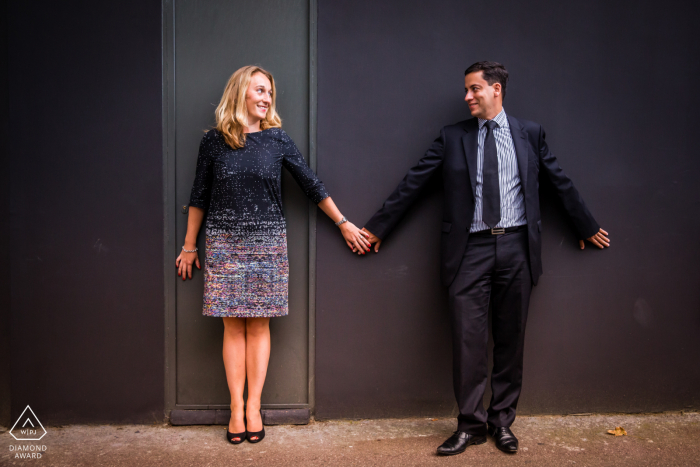 Couple de Paris se tenant la main contre un mur lors de leur séance de portrait de fiançailles