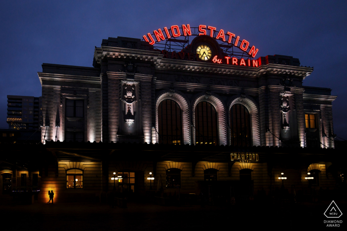 A silhueta de um casal contra o prédio da Union Station de Denver durante as fotos de noivado no centro da cidade