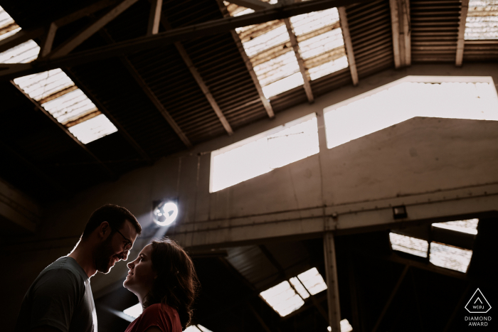 O casal troca um olhar genuíno, enquanto sob um raio de luz muito leve em uma garagem abandonada em Leiria, Portugal