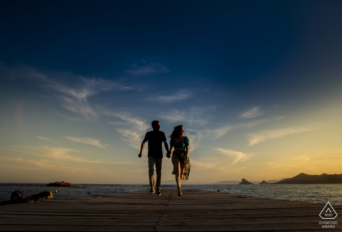 A couple is Playing on the jetty during their sunset Aguilas - Spain engagement photo shooting session