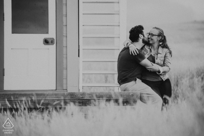 a Godley Head, Christchurch NZ Couple sitting together sharing an embrace during a black and white engagement shoot