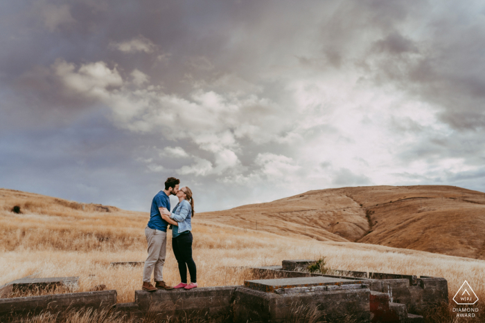 Godley Head, Christchurch NZ Coppia baciarsi sotto le nuvole in un campo aperto