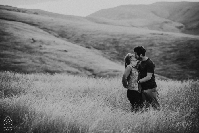 Ein Paar küsst sich in den Hügeln während ihres Fotoshootings in Godley Head, Christchurch, Neuseeland