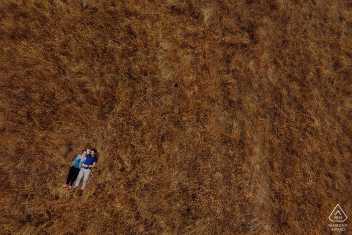 Godley Head, Christchurch NZ Verlobungsdrohnenporträt eines Paares, das im Gras liegt