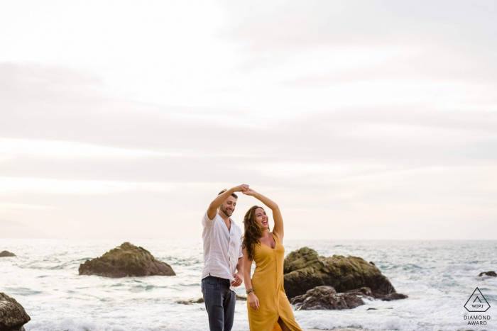 an engaged couple is Dancing on the beach Playa Conchas Chinas, Puerto Vallarta, México during a photo session